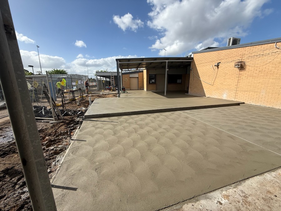 A large concrete slab beside a brick building with a covered area