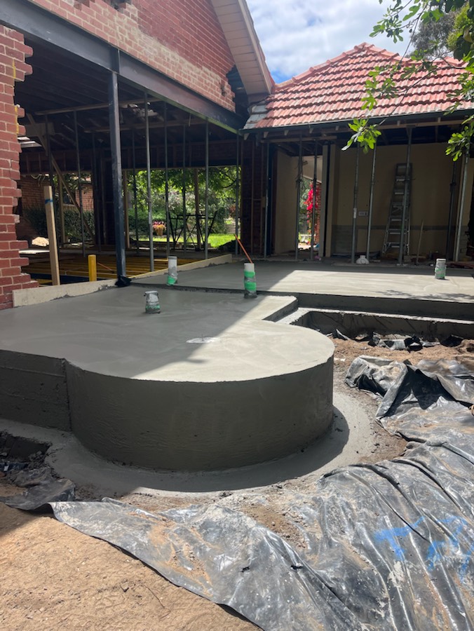 A raised concrete slab with a curved edge at a brick house extension