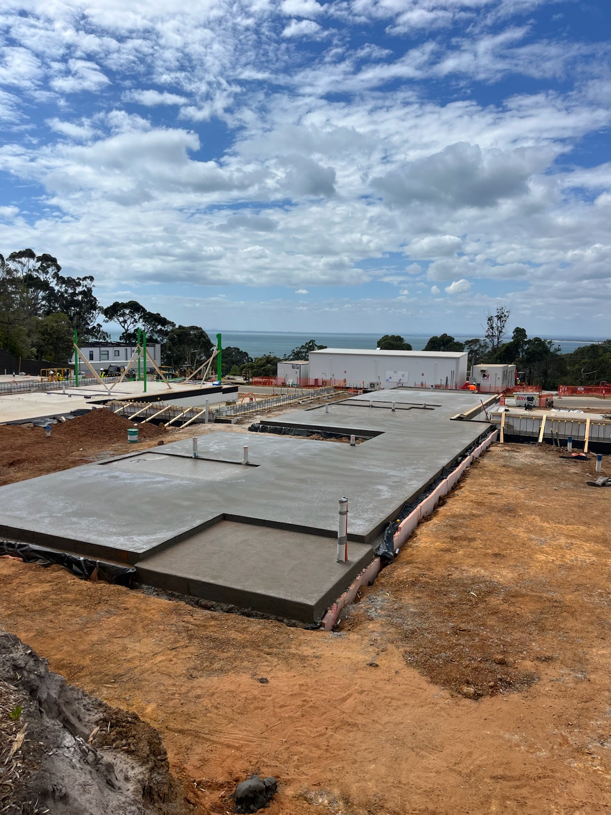 A house slab poured by Elev8 Concrete Constructions for The Block, on a sloping site with the bay in the distance