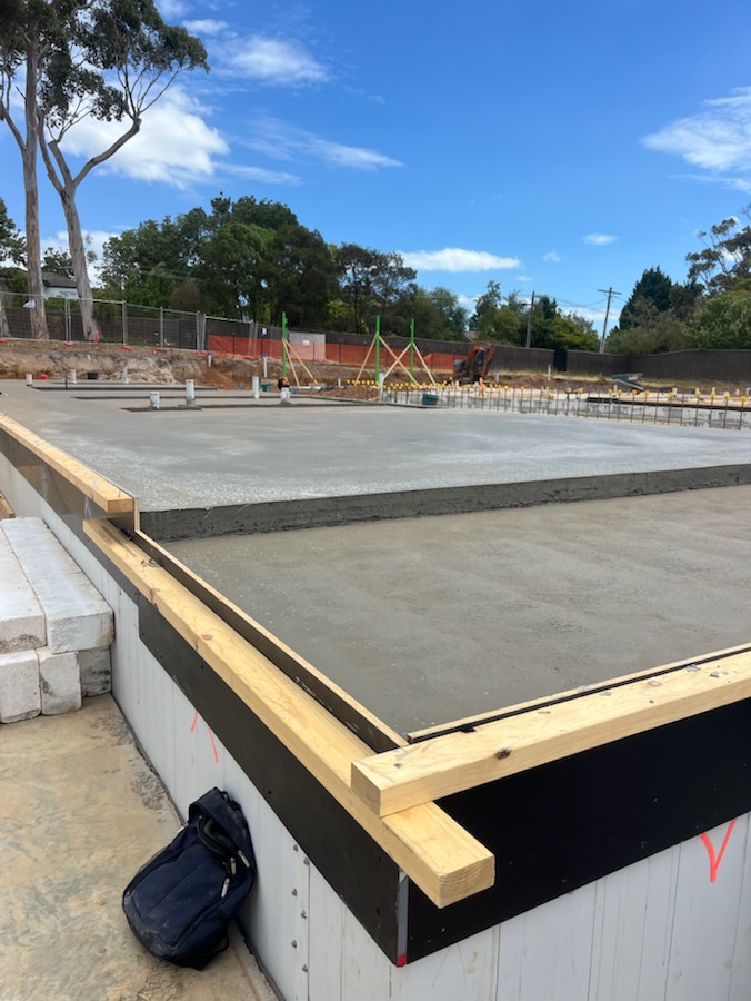 A large concrete slab with stepped levels and edge formwork under a blue sky