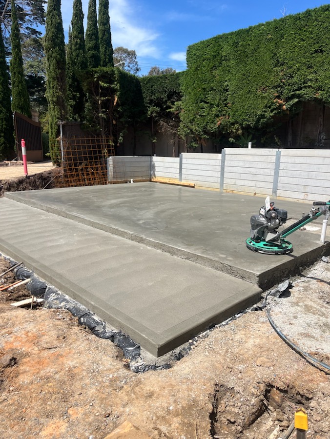 A finished concrete slab with a stepped edge and a power trowel sitting on it